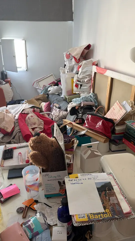 Chambre remplie d'objets et de sacs empilés avant intervention